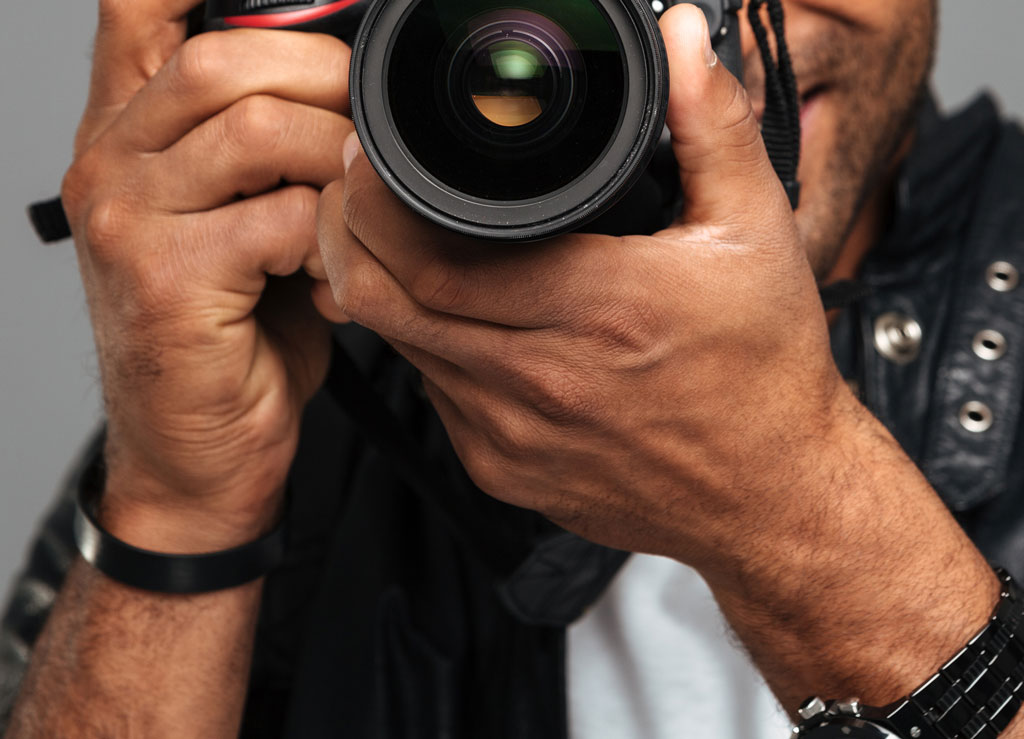 Young photographer holds a camera. Studio portrait with lighting equipment in the background